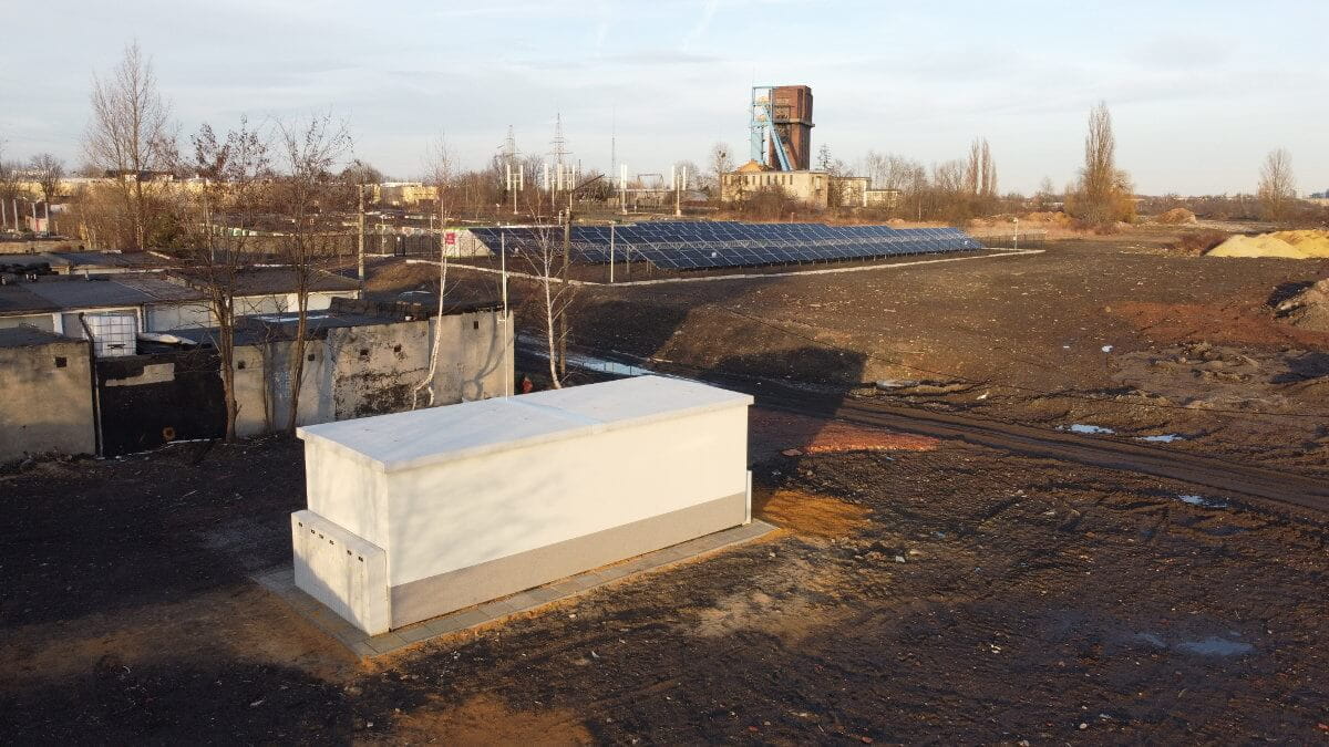 Biały budynek innowacyjnej podstacji dystrybucyjnej, w tle pozostałe obiekty mikrosieci i szyb d. kopalni Szombierki.